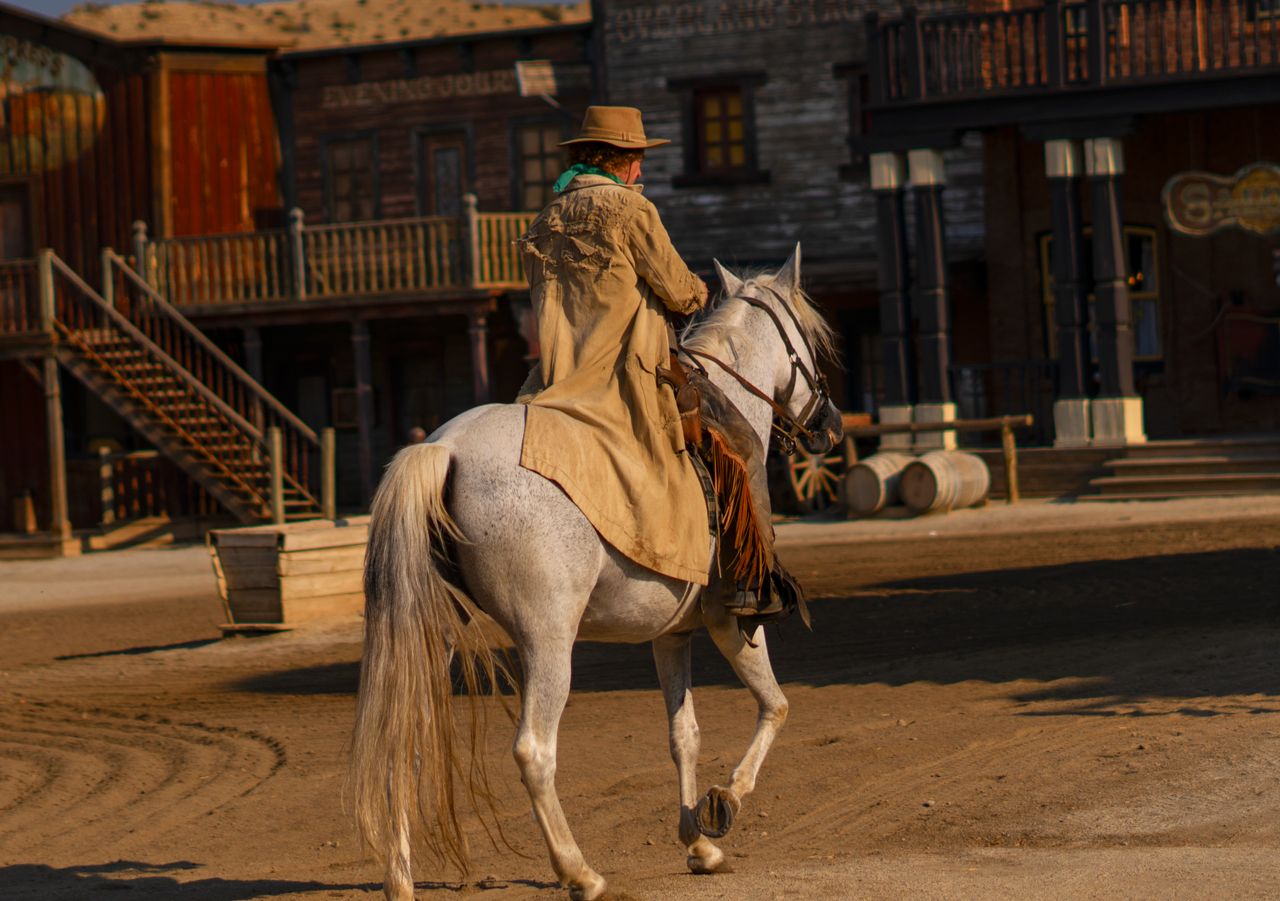 A cowboy rides a white horse in Mini Hollywood theme park, Tabernas, Spain, capturing the essence of the Wild West.