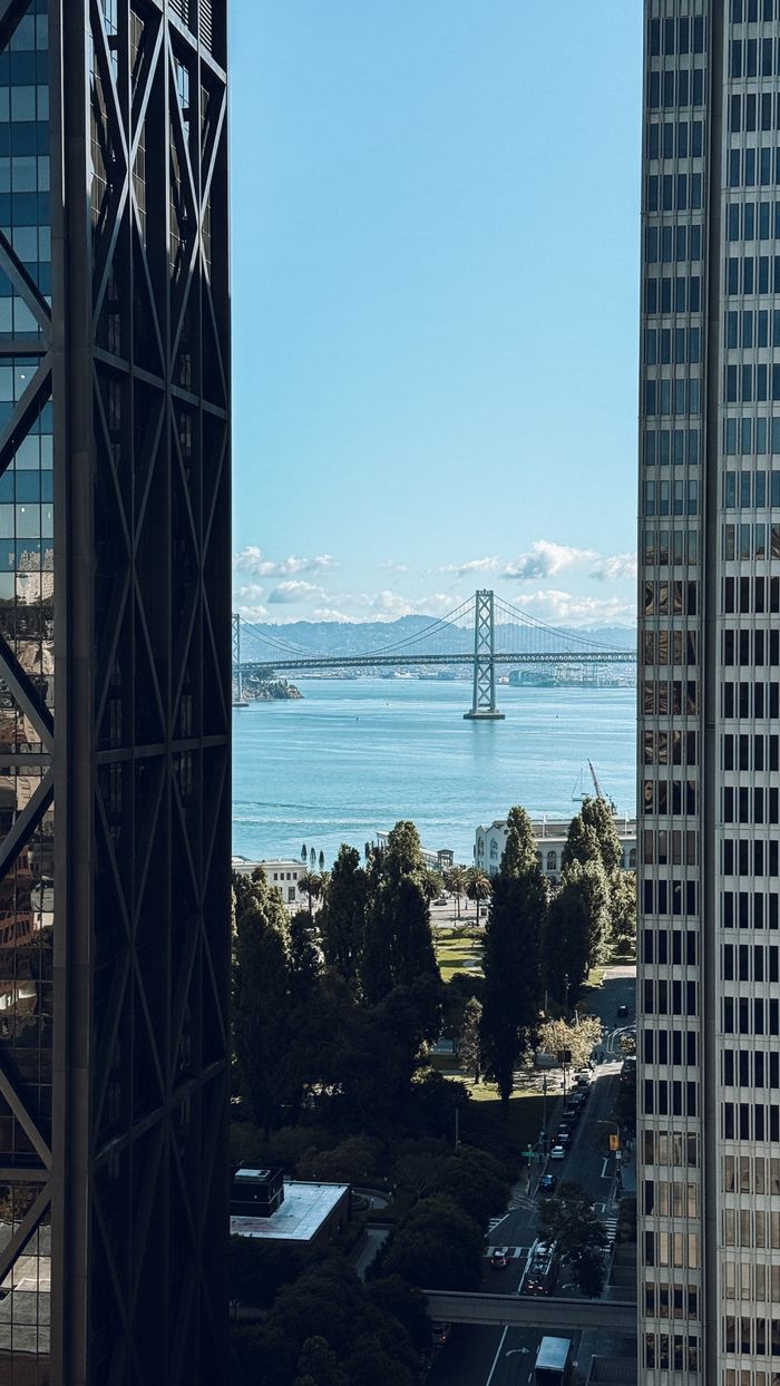 gallery-05 Scenic view of Bay Bridge framed by downtown skyscrapers, capturing a clear day in San Francisco.