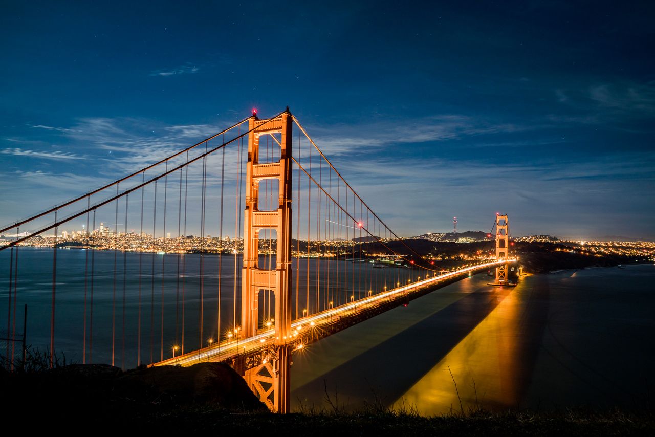 gallery-01 Stunning view of the illuminated Golden Gate Bridge at dusk against a vibrant cityscape.