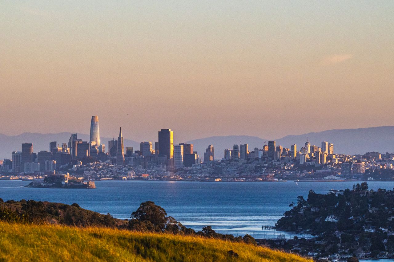 Scenic view of San Francisco skyline and bay during sunset with iconic landmarks.