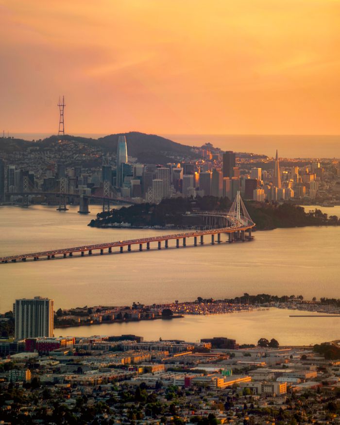 Explore the iconic San Francisco skyline and Bay Bridge during a stunning sunset with vibrant colors.