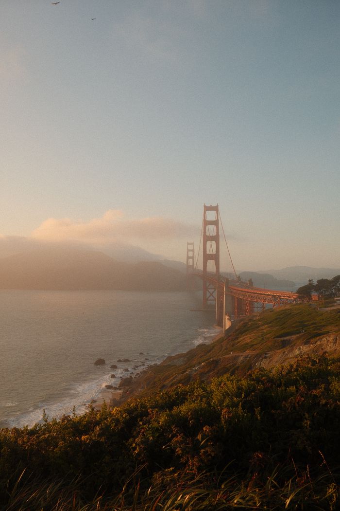 Dramatic view of the Golden Gate Bridge at sunset with misty shores.